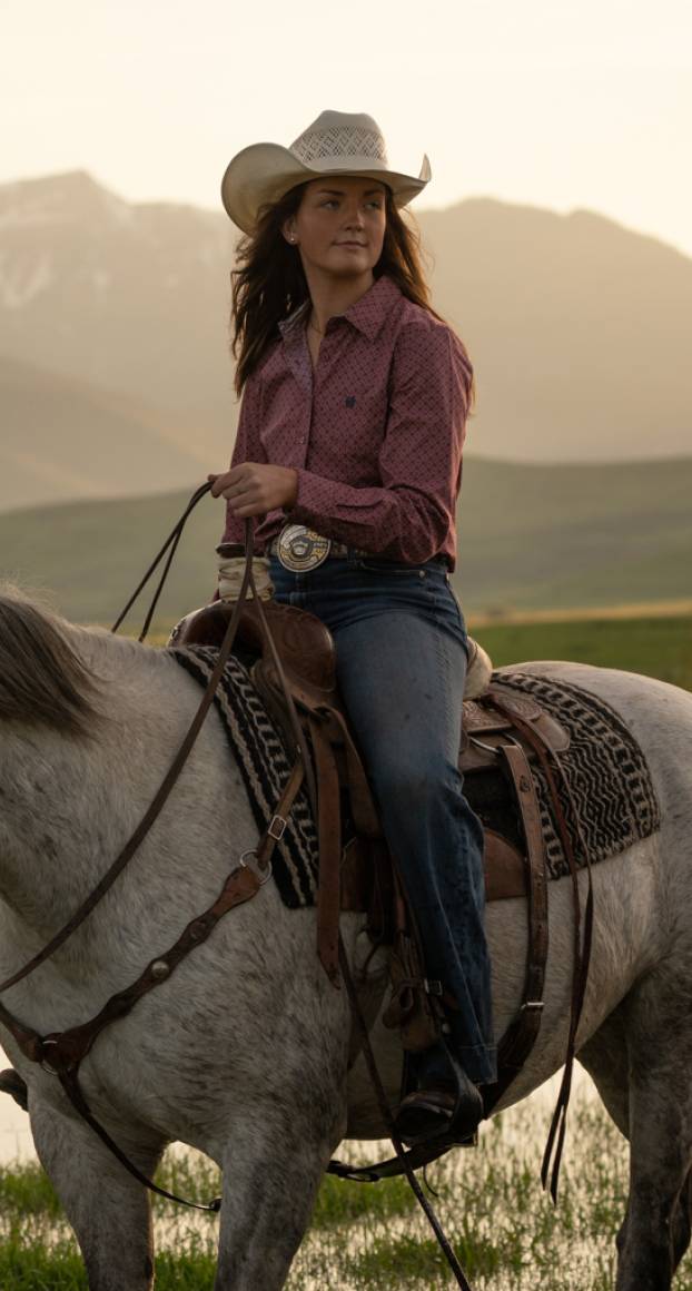 A woman wearing a cowboy hat riding on horseback in the Gros Ventre wilderness.